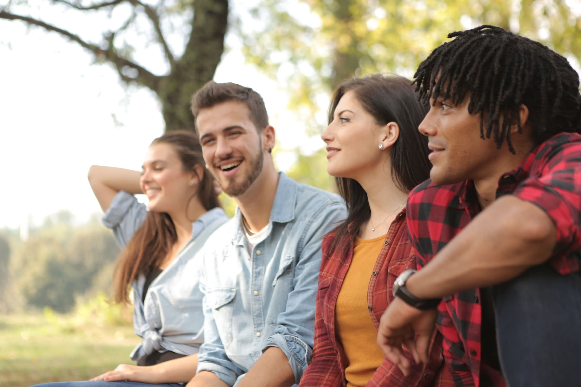 Four youth just chilling and having a chuckle whilst sitting outside on a nice day