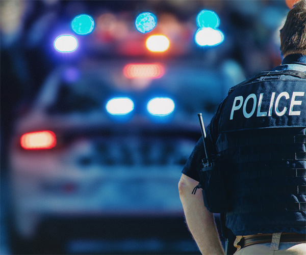 back of police officer and blurred police lights in the background